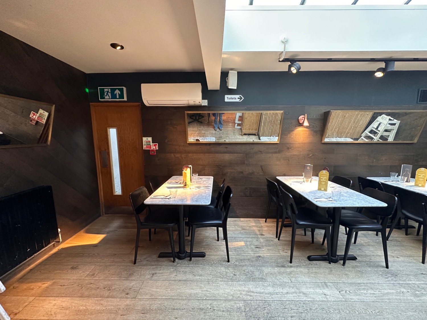 From end of open kitchen facing straight. Tables and chairs ahead.