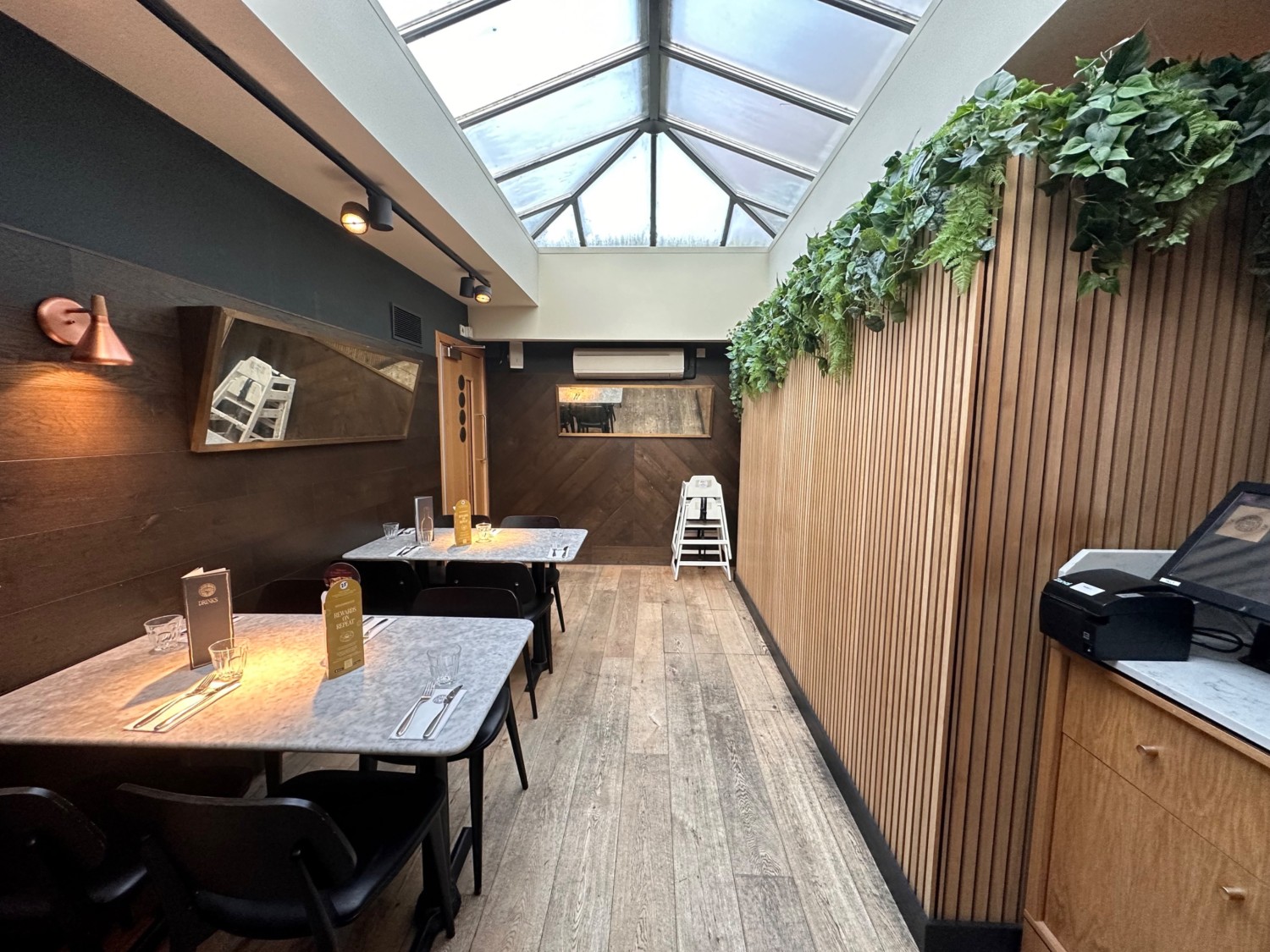 From end of open kitchen facing right. Tables & chairs along left, door to toilet behind.