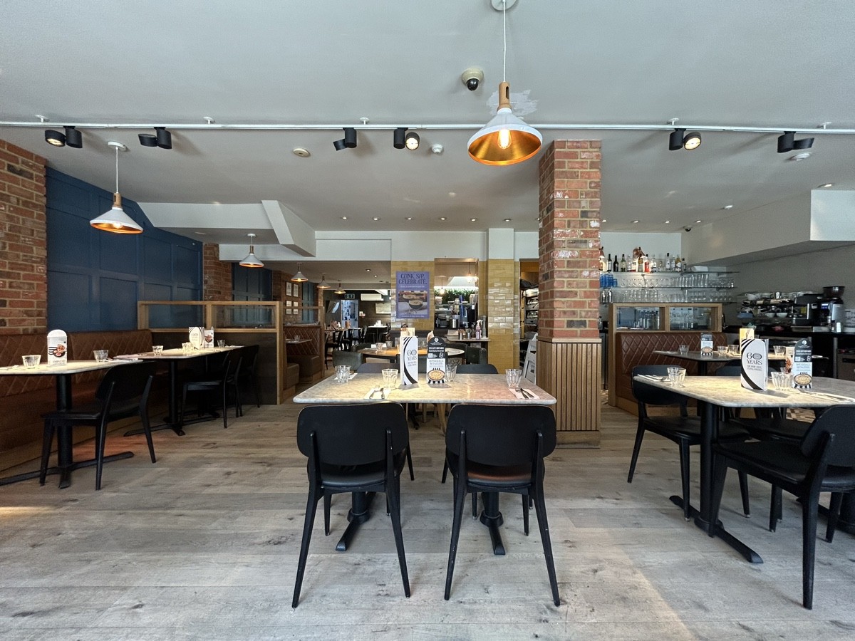 From start of tables facing left. Tables and chairs on right and ahead in centre. Half booths on left.