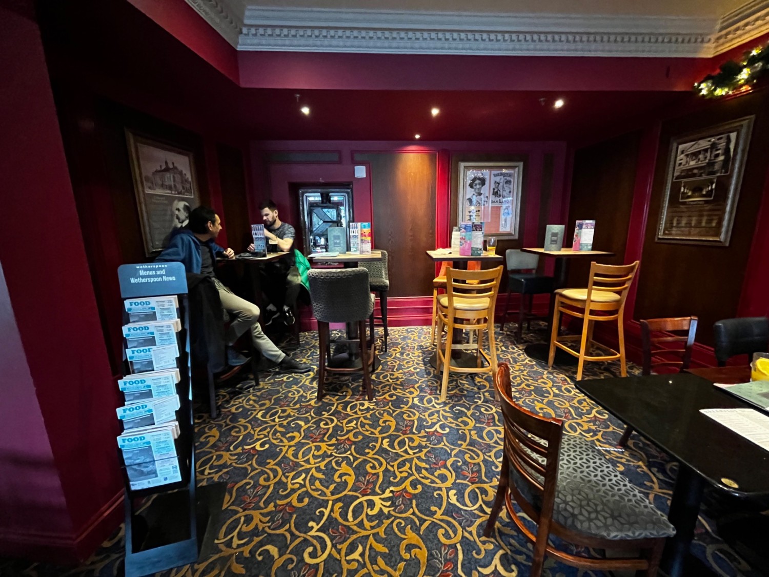Facing left from archway. High tables with backed stools on wall ahead.