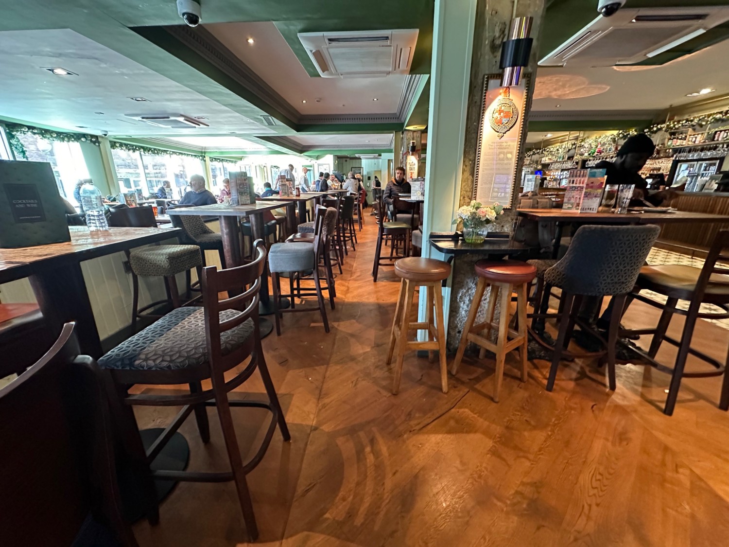 From entrance facing left. High tables, chairs and stools along left and right. Columns along right.