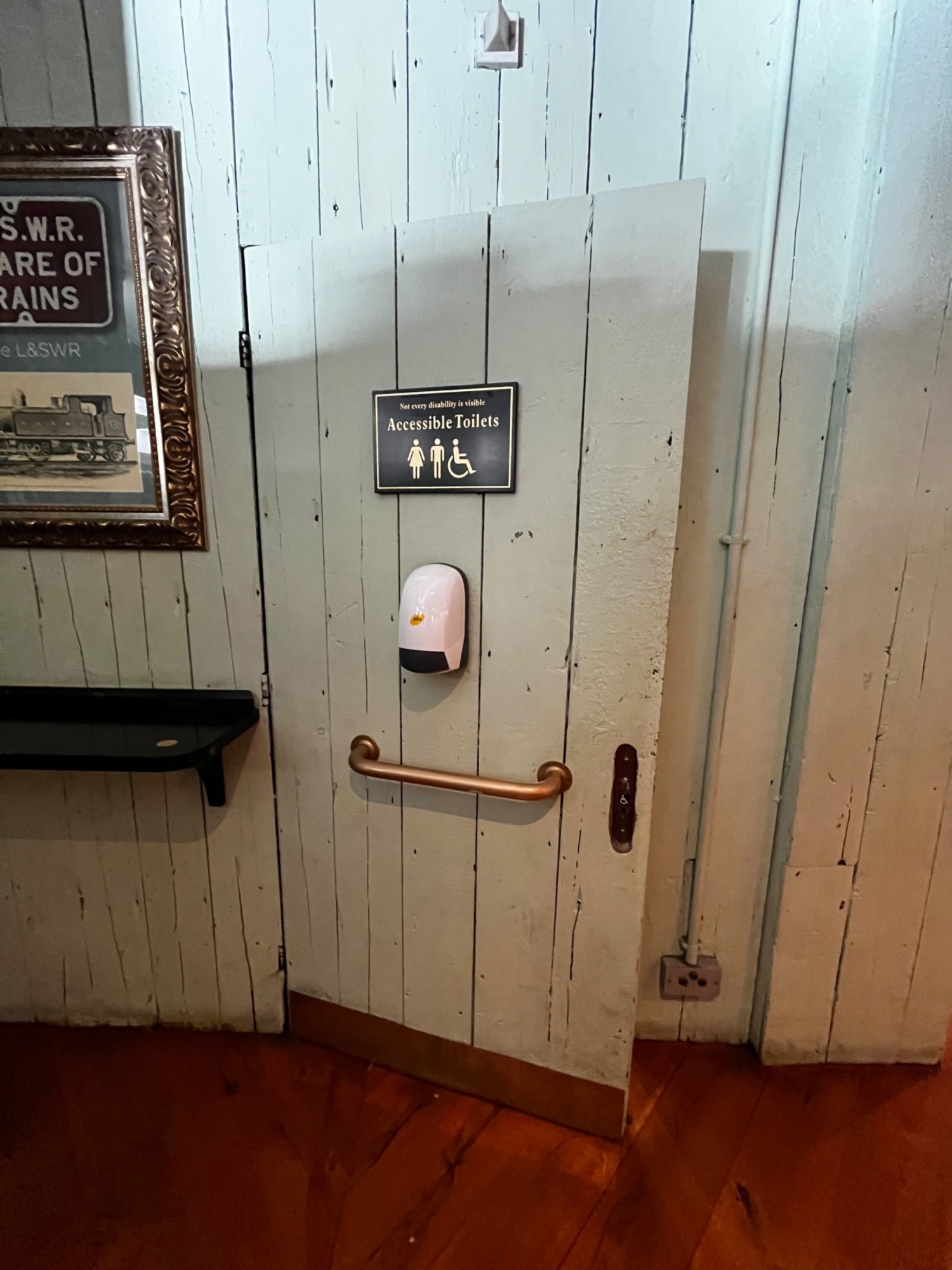 From back of main area facing steaight. Green accessible bathroom door ahead. Gold grab rail in centre. Radar keyhole to right of door.