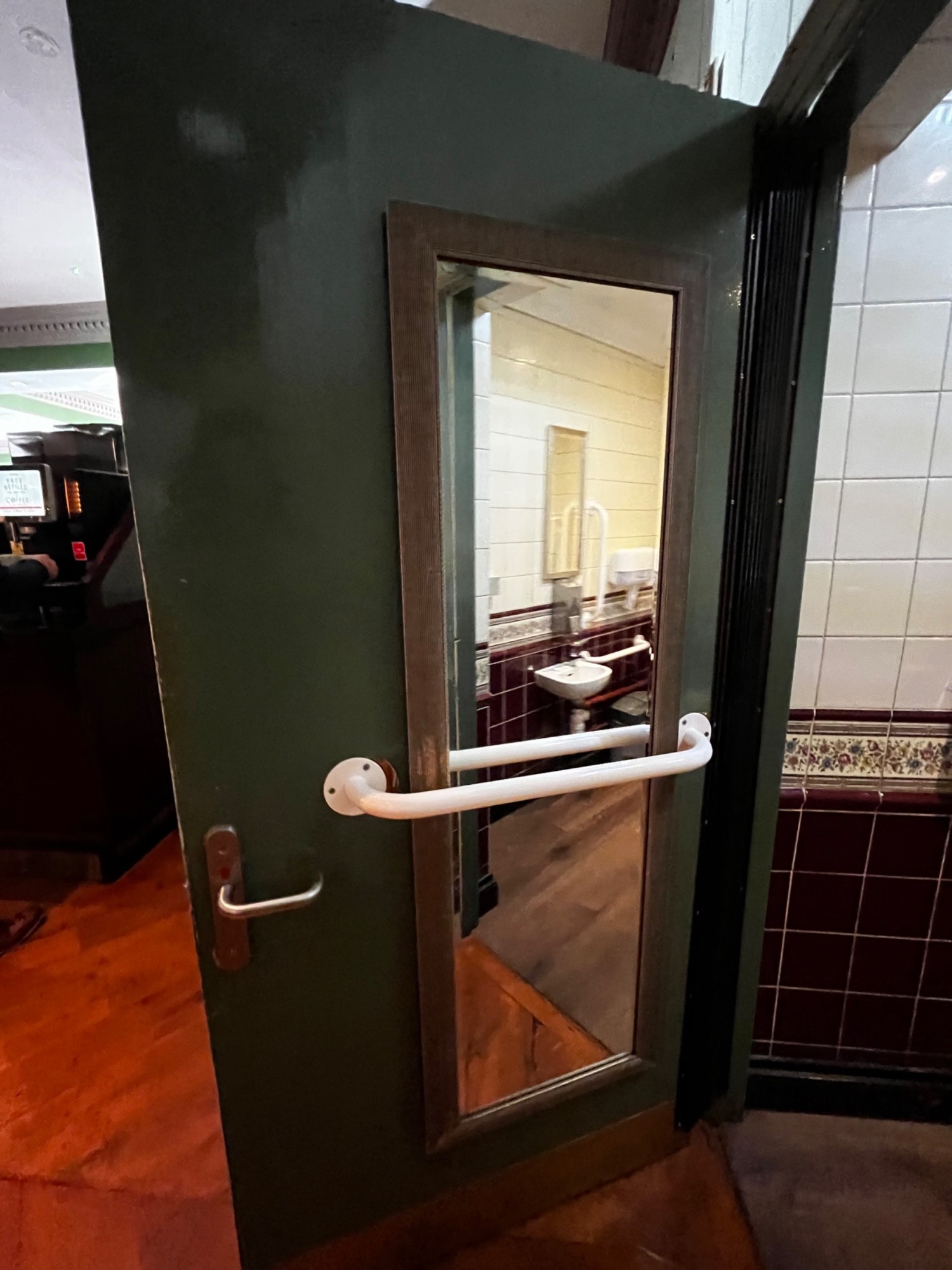 Back of door. White grab rail and mirror in centre. Push silver handle from left to open.