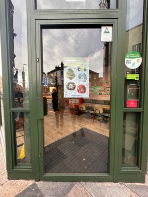 Glass door with green, metal frame. Push from left to open.