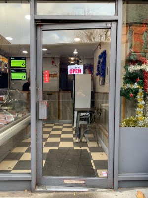 Glass door with grey metal frame. Push from grey handle on left to open.