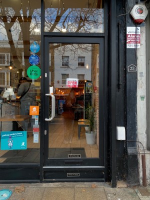 Glass door with black frame ahead. Push silver handle on left of door to open.