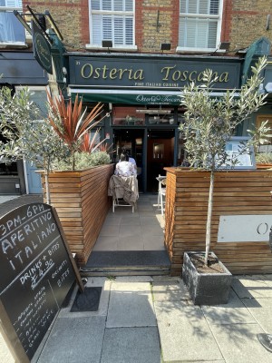 Opening to outdoor seating area. Wooden planters on left and right of opening.