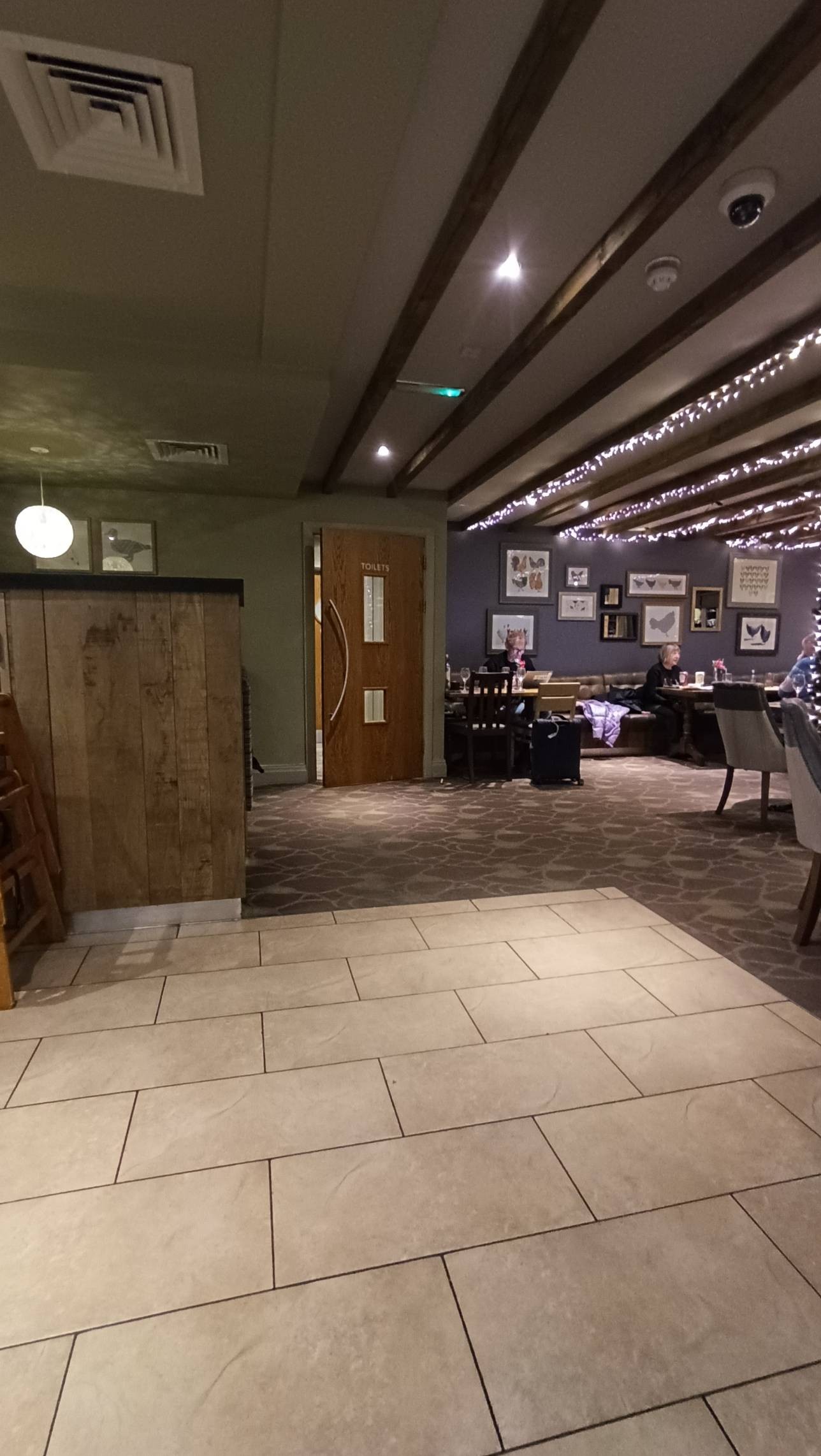Wooden door through to the toilets, small glass panels, heavy door opens left to right shows long bench area and tables as described in photo above,
