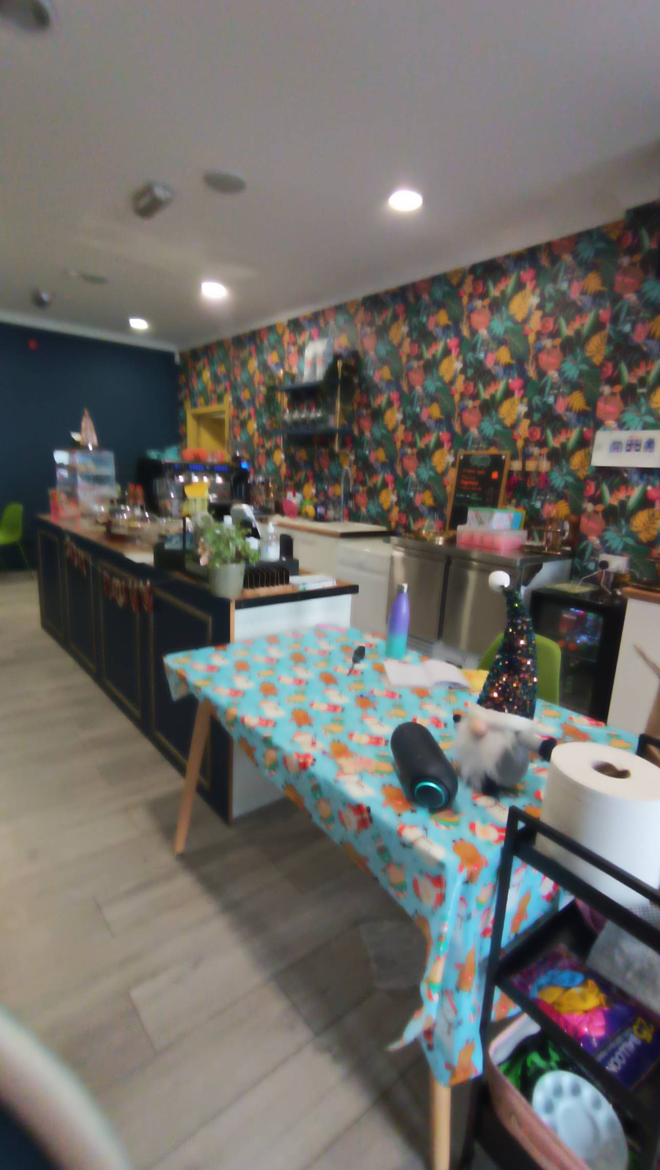 Standing height counter top, cakes and confectionery on top of counter, colour contrasting counter and floor.