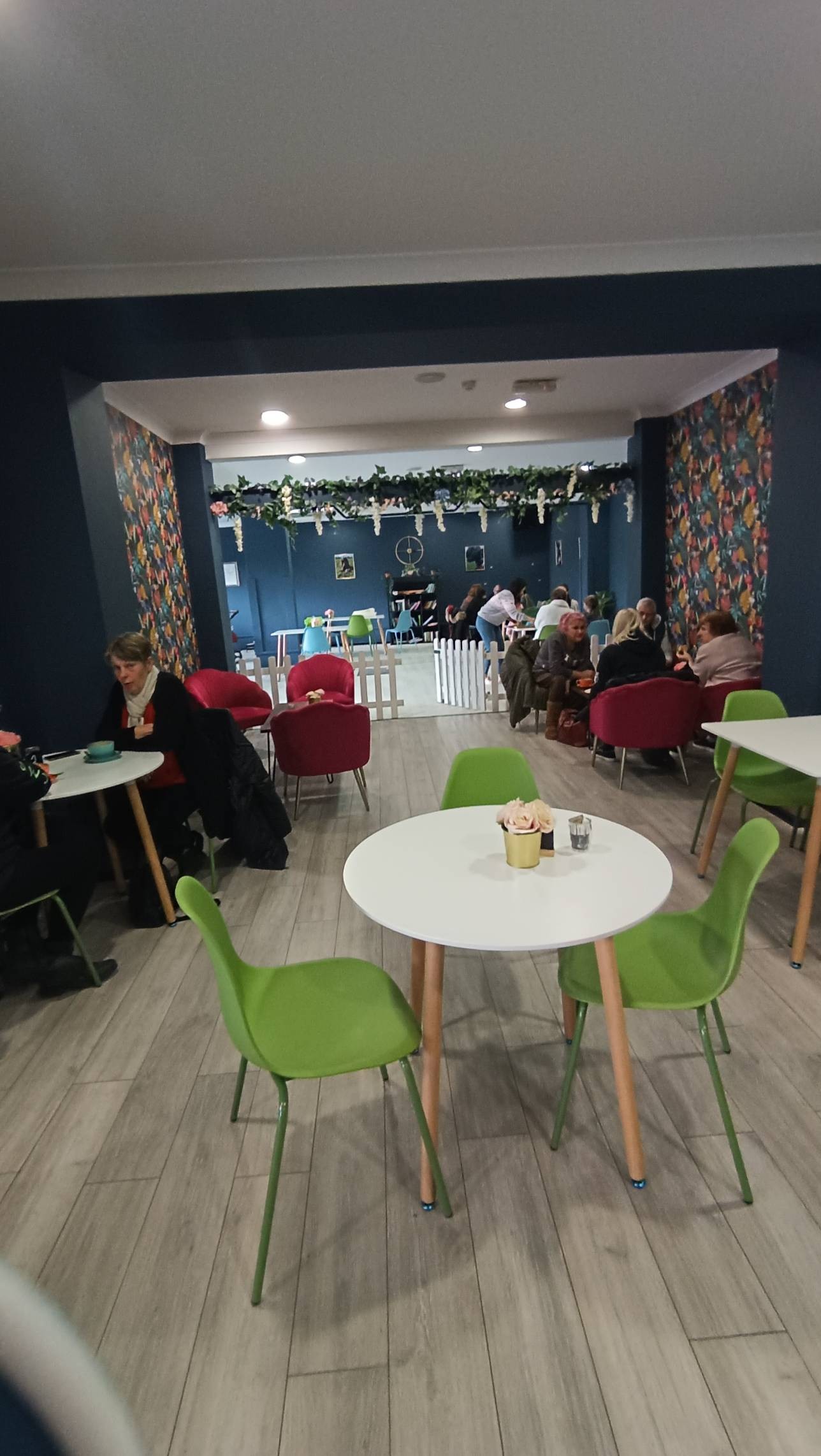 Eating area, mixture of seated height tables and low tables with padded chairs, gated area through small low fence for dog cafe, seated height tables
