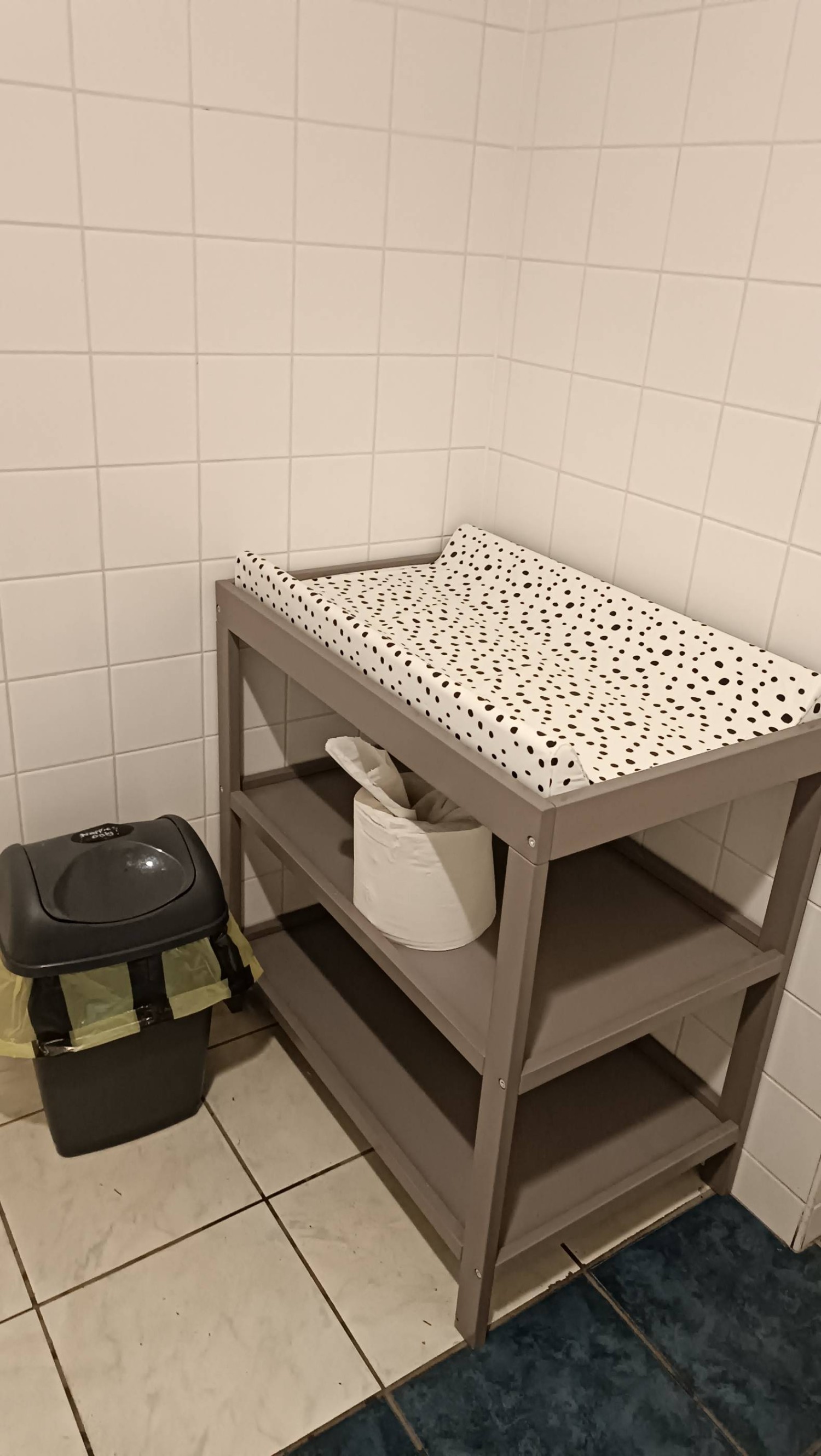 Children's changing table in corner of room. Colour contrasted with white tiled wall.