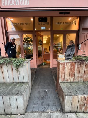 Pathway to main door. Obstruction to right and left. Built in ramp down centre. Pink framed glass door with metal handle to right. Push to open.