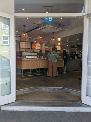 Glass door with white frame and metal handles in centre. Pull to open.