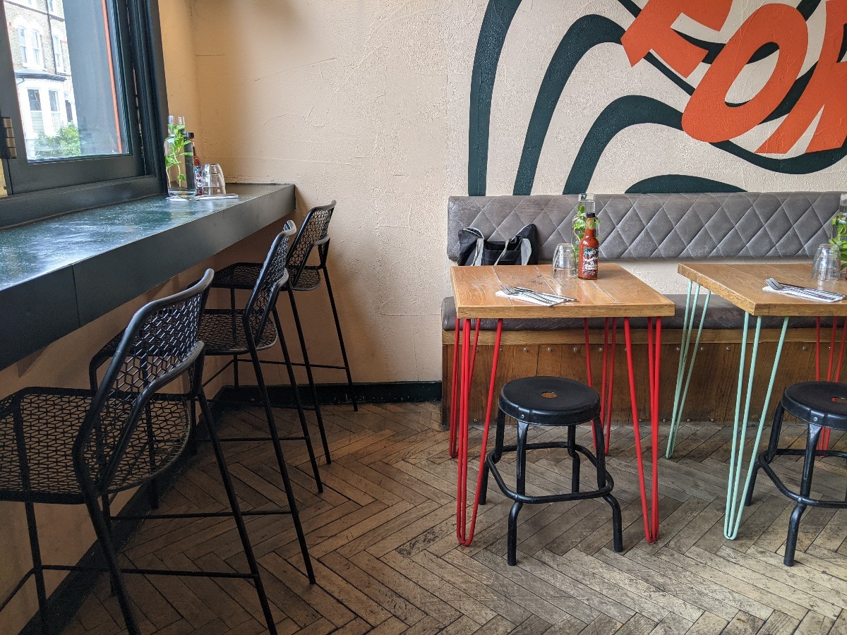 From entrance facing left. High table with stools along left. Half booths with stools on right.