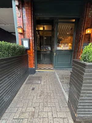 From pavement on left side of venue facing right. Planter on left and right. Alternative entrance ahead.