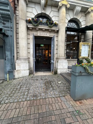 Double glass doors with handles in the middle, pull to open. Built in cobbled floor ramp to entrance doors. Outdoor area to right.