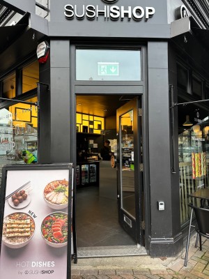 One step followed by glass door with black frame. Push from left to open