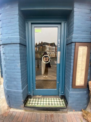 Glass door with blue, wooden frame. Push from right to open.