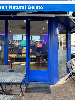 Ramp up to glass door with blue frame. Push from left to open