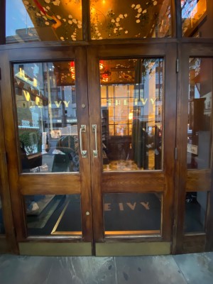 Glass doors with brown, wooden frame. Pull golden metal handles in middle to open.