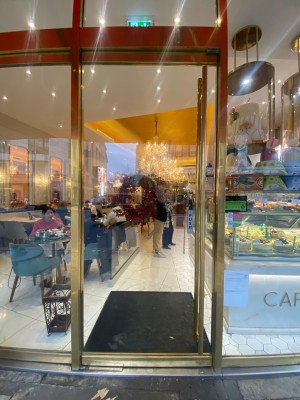 Glass door with golden metal frame ahead. Push golden metal handle on right to open.
