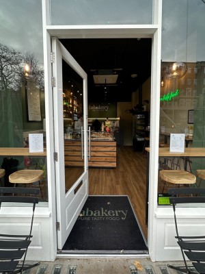 Glass door with white frame ahead. Push silver handle from right to open.