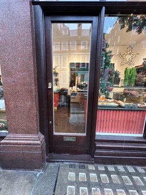 Glass door with black, wooden frame. Push from left to open.