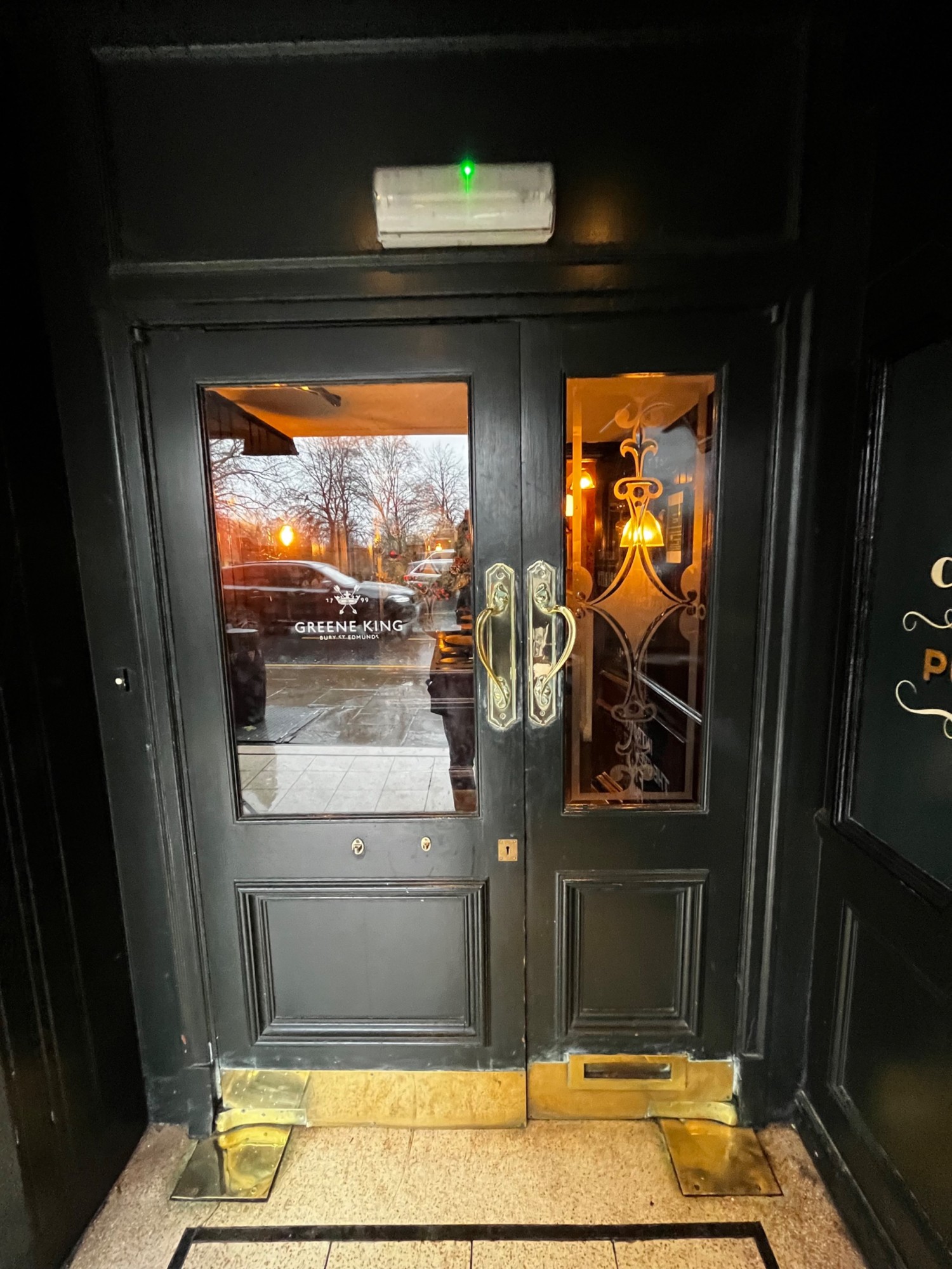 From high table, facing straight. Glass doors with black, wooden frames ahead. Pull golden handles from middle to open.