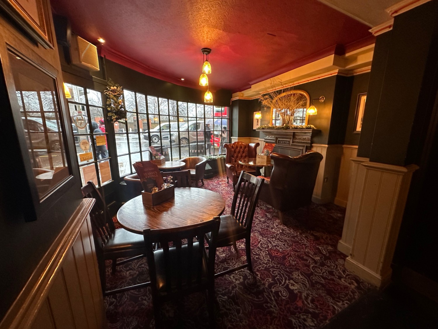 From high half booth facing left. Tables and chairs spread out ahead. Armchairs at back right.