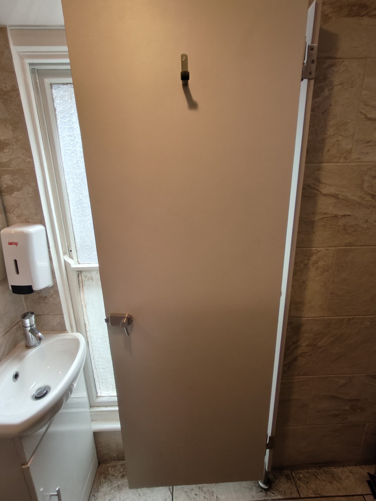 Back of door. High hook at centre. Push from left to open.