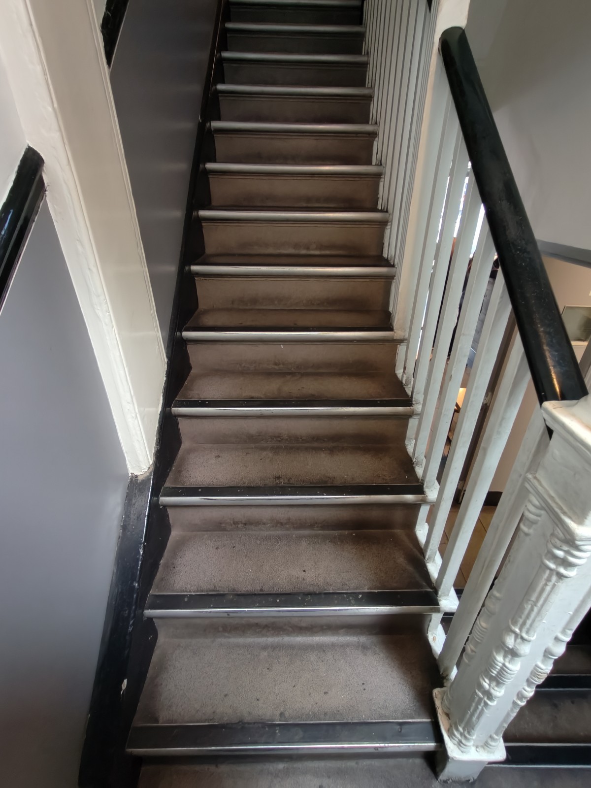 From end of first landing facing right. Stairs continue up. Black handrail on right.