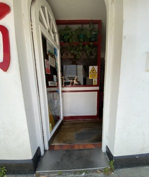 Glass door with white frame ahead. Push from metal handle on right to open.
