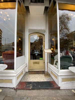 Glass door with pale yellow frame. Push from right to open.