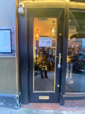 Glass door with black frame. Push from right to open.
