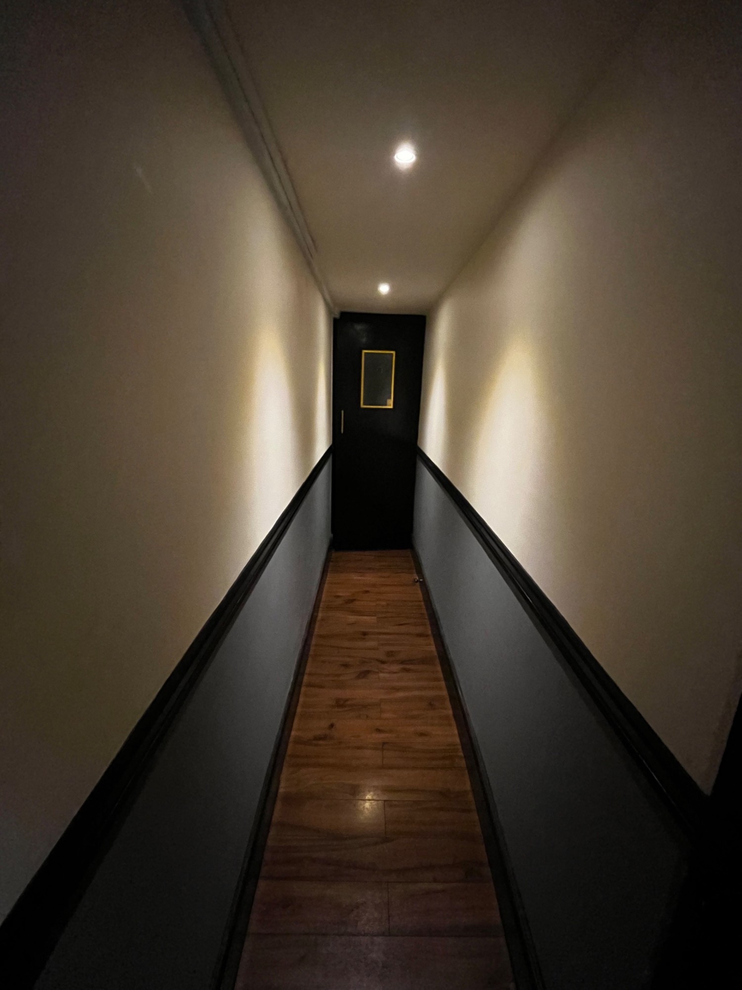 Facing left from entrance. Second black wooden preceding door at end of hallway ahead. Pull from left to open.