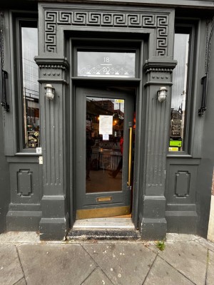 Glass door with grey frame. Push from right to open.