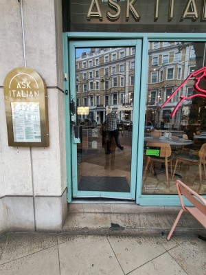Blue framed glass door. Push metal handle on left to open.