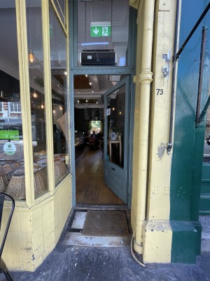 Blue wood-framed glass door. Push from brass handle on left to open.