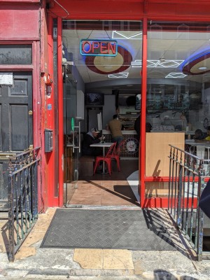 Ramp up to glass door with red frame. Push from metal handle on right to open.