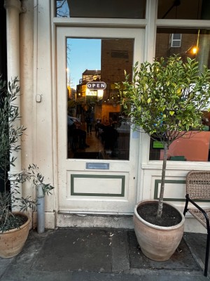 Glass door with white wooden frame. Push from right to open.