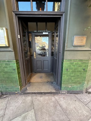 Facing two sets of doors. First double glass doors, propped open. Single glass door after. Pull handle on right to open.