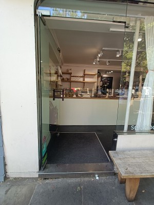 Glass door with black, metal handle on right. Push to open.