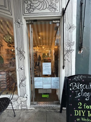 Glass door with white frame. Push silver handle from left to open. A-frame to right.
