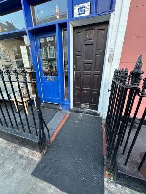 From street, facing restaurant front. Enter through opening in front railings. Restaurant door to slight left.
