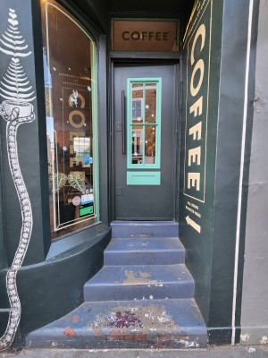 Four steps up to green door with glass panel. Push black handle on left to open.