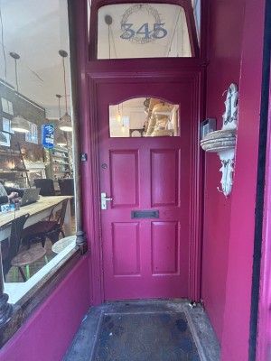 Pink wooden door ahead. Push from handle on left to open.