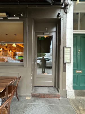 One step up to glass door with brown doorframe. Pull from left to open