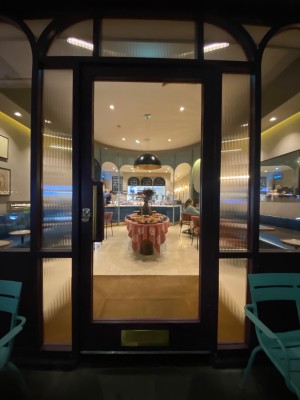 Glass door with purple frame. Push golden handle from left to open.