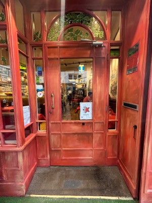 Red door with glass panel ahead. Pull from left to open.