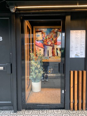 Glass door with black frame ahead. Push door from handle on right to open.